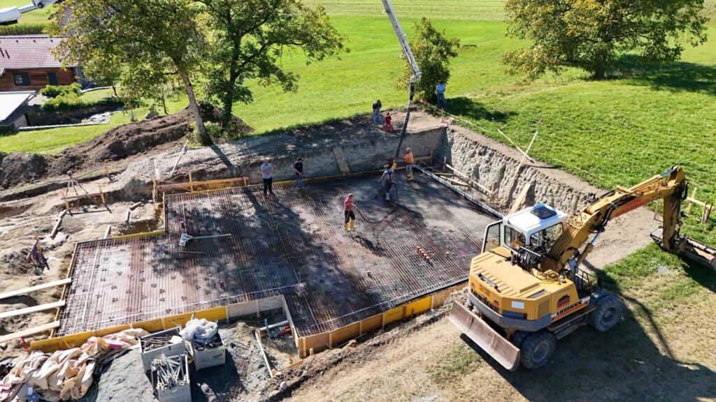 Luftaufnahme einer Inspektion der Baustelle in Feldkirchen, Kärnten, mit Fokus auf vorbereitete Bodenplatte und umliegende Erdarbeiten – Keyword: Inspektion Baustelle Drohnen Feldkirchen Kärnten